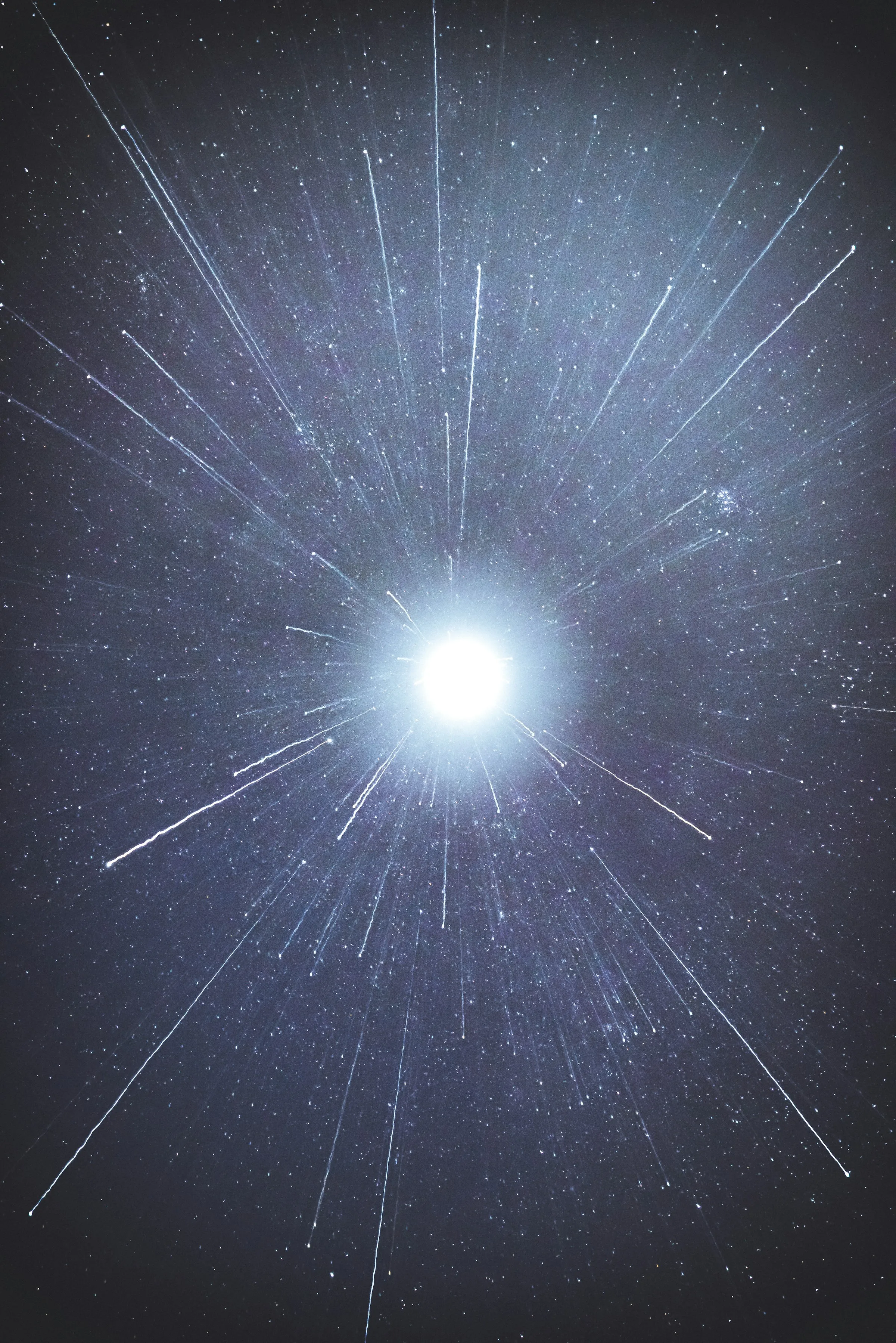 A single bright star burning in a dark sky, its light streaking outward across the frame