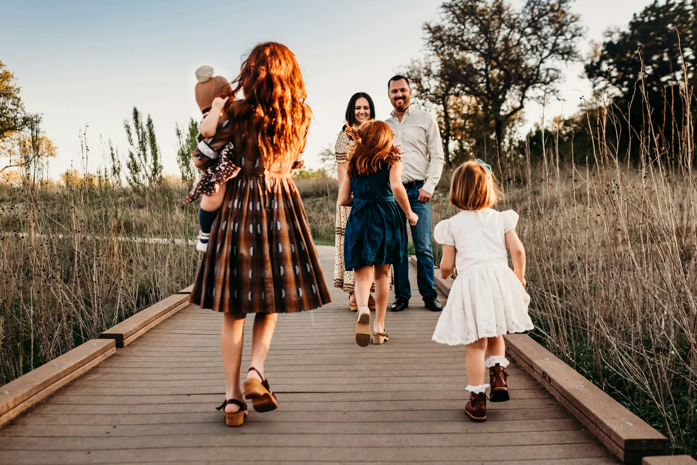 A family walking together down a boardwalk through tall grass