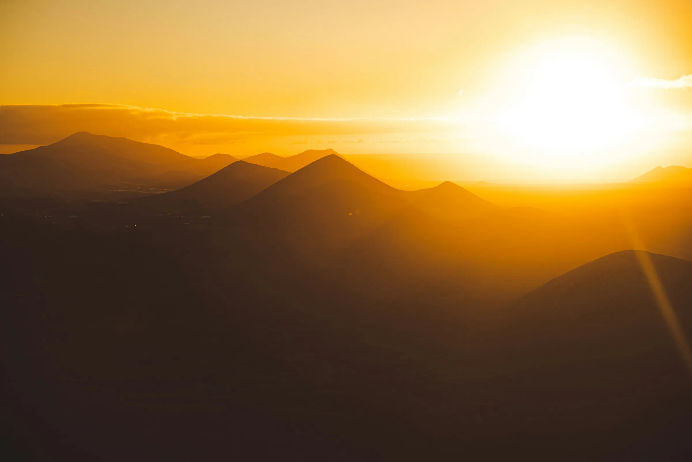 Ridge after ridge of mountains fading into haze under a low sun